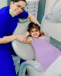 Dentist with a smiling young girl in the dental chair